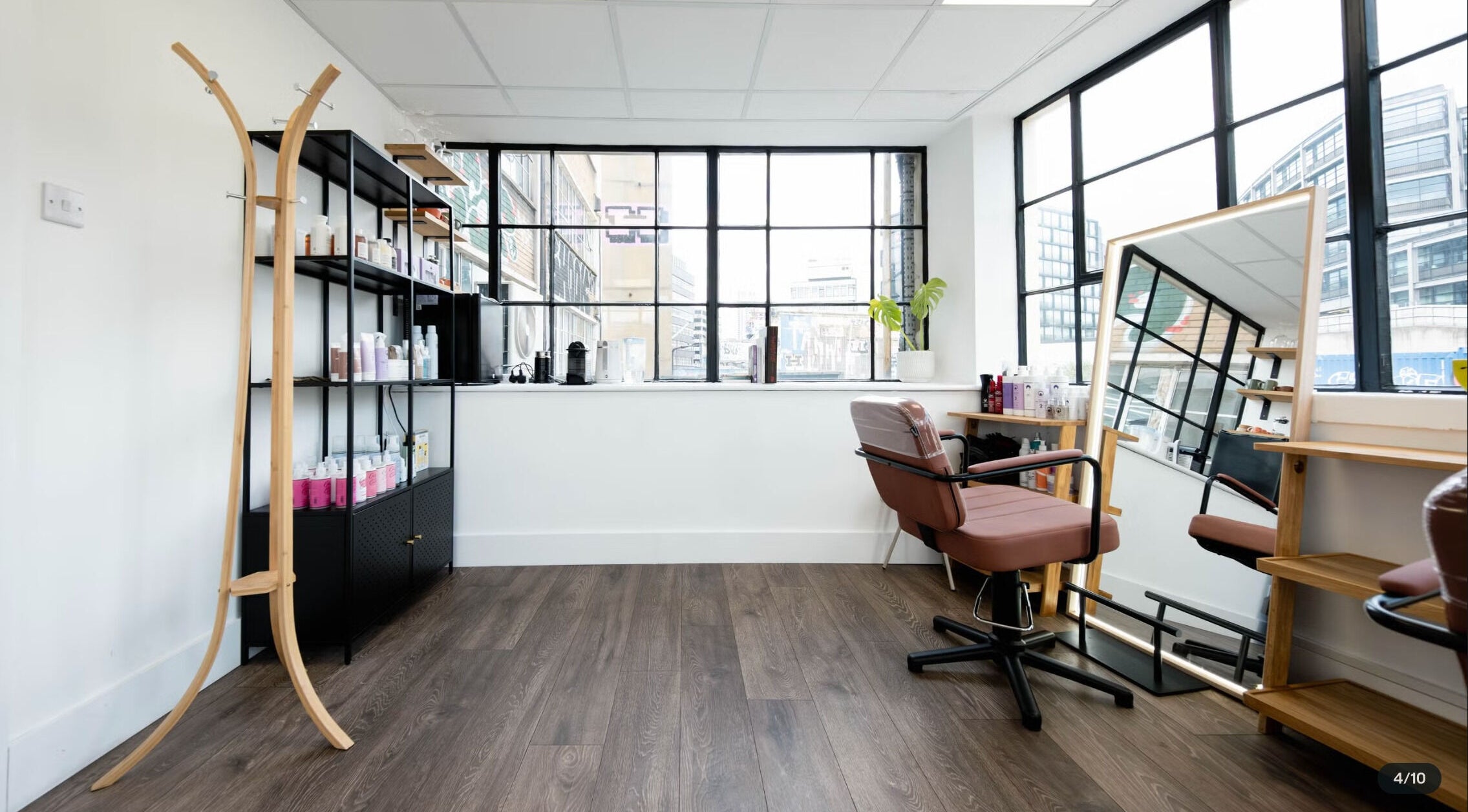 Bright salon space at Logvina Hair, London, England, GB with a modern chair, mirror, and product shelves.