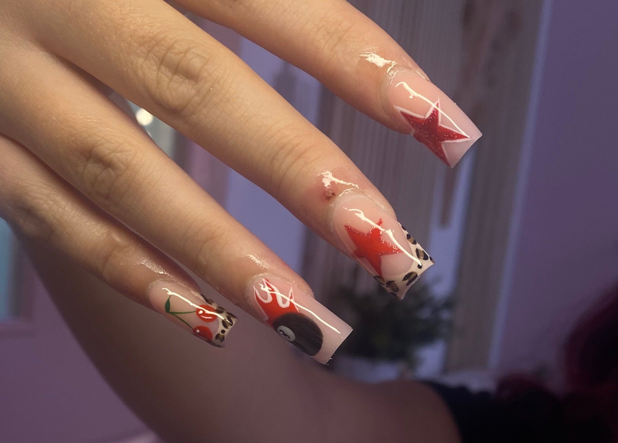 Unique nail art at Ink and Polish in Barnsley, England, GB, featuring stars and cherries on manicured nails.