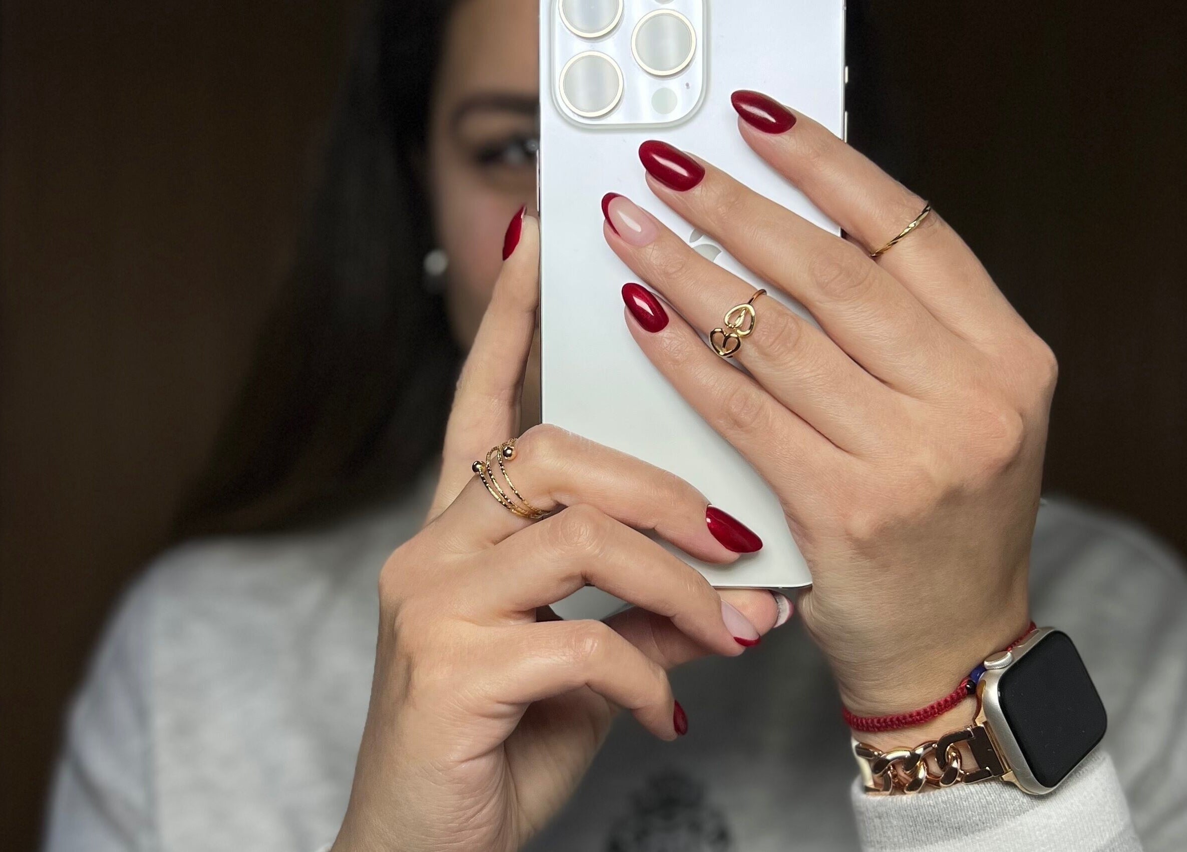 Uñas rojas elegantes en Dubíe Studio, Providencia, Región Metropolitana, CL, sosteniendo un teléfono.