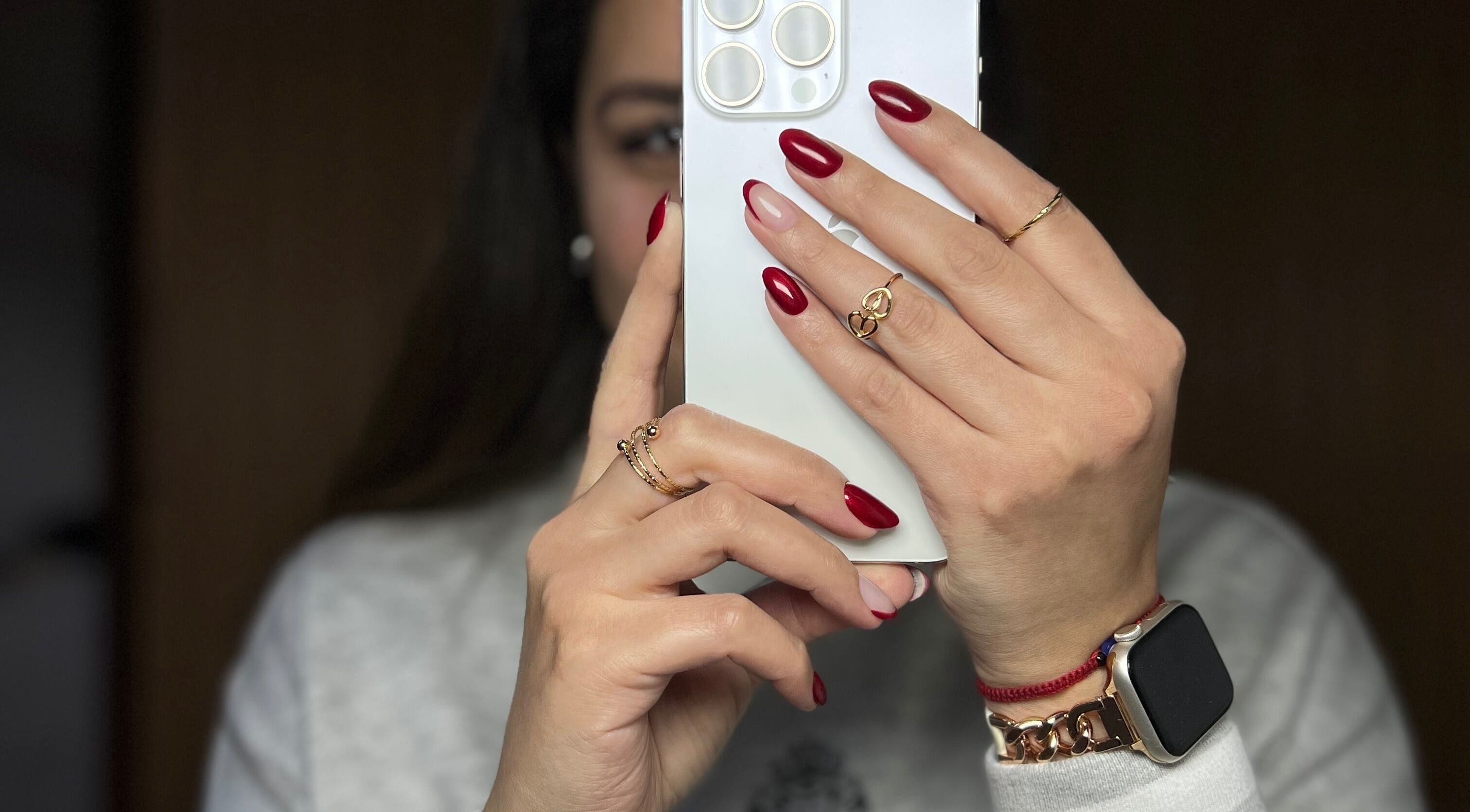 Uñas rojas elegantes en Dubíe Studio, Providencia, Región Metropolitana, CL, sosteniendo un teléfono.