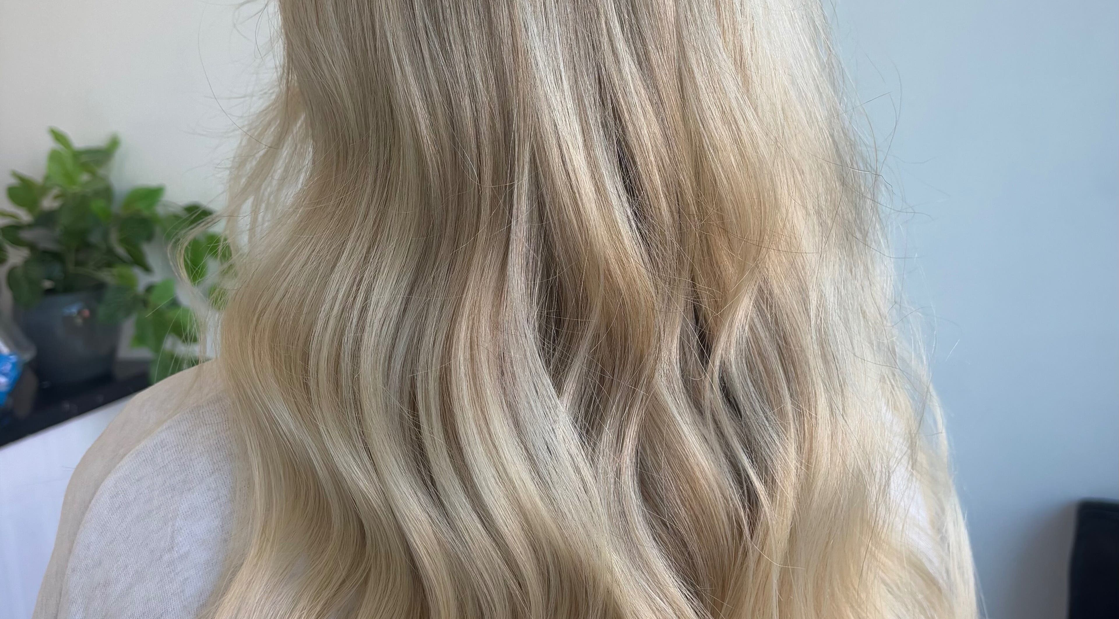 Beautiful blonde waves styled at Hair by Emma Sturt in Beenleigh, Queensland, AU with plants in the background.