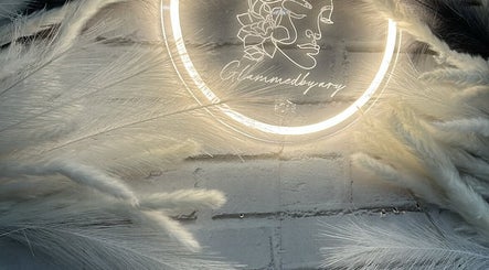 Logo iluminado Glammedby.Ary em parede de tijolos com plumas na decoração, Santo António Da Charneca, Setúbal, PT.