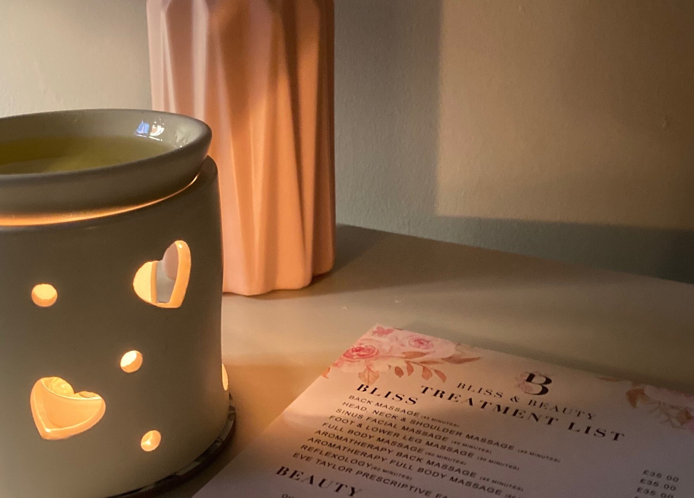 A lit wax warmer with a treatment menu at Bliss & Beauty by Nikki at Serenity, Leek, England, GB.
