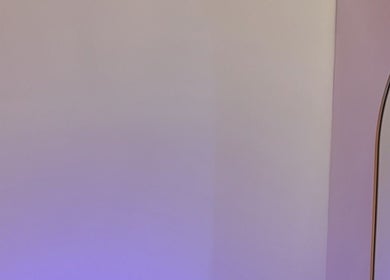 Elegant curved mirror at Enhancedbym, Birmingham, England, GB with soft purple lighting.