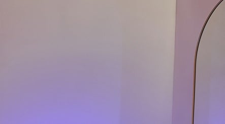 Elegant curved mirror at Enhancedbym, Birmingham, England, GB with soft purple lighting.