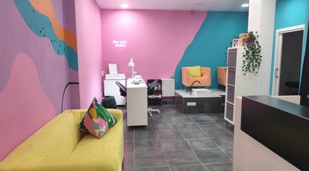 Interior colorido de Paula Infante Nails en Benalmádena, Andalucía, ES con sofás y estación de manicura.
