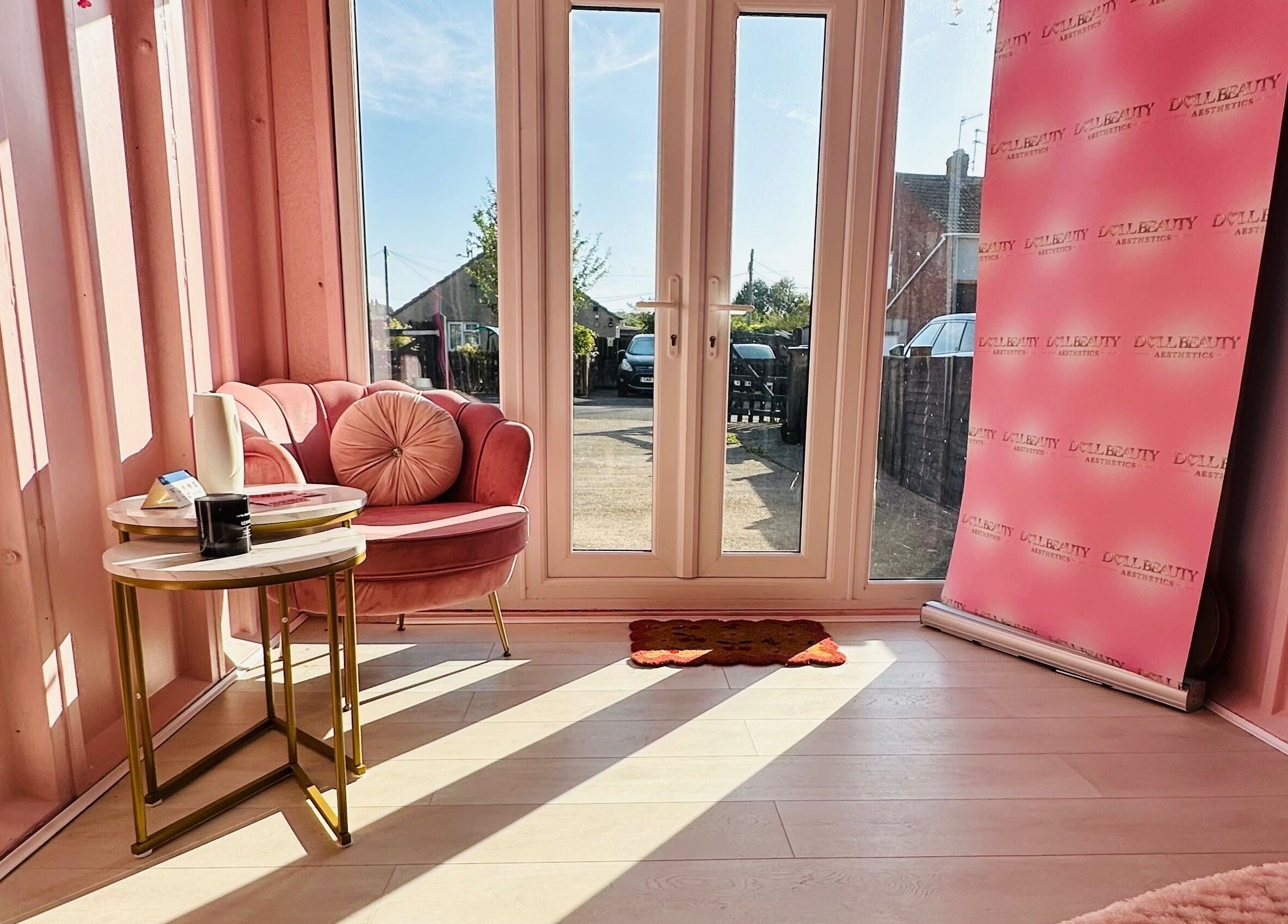 Cozy pink seating area with branded backdrop at Doll Beauty Aesthetics & Training Academy, Cleeve, England, GB.