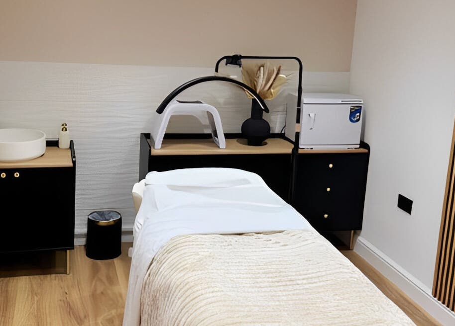Modern treatment room at Naked Beauty in North Weald Bassett, GB, featuring sleek decor and a comfortable massage bed.