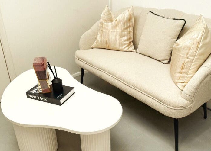 Comfortable beige seating and modern table at Naked Beauty, North Weald Bassett, GB, offering a relaxing ambiance.