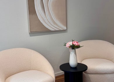 Coin salon chic chez MC Studio Hair Artist, Lausanne, Vaud, CH, avec fauteuils crème et vase floral.