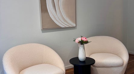 Coin salon chic chez MC Studio Hair Artist, Lausanne, Vaud, CH, avec fauteuils crème et vase floral.