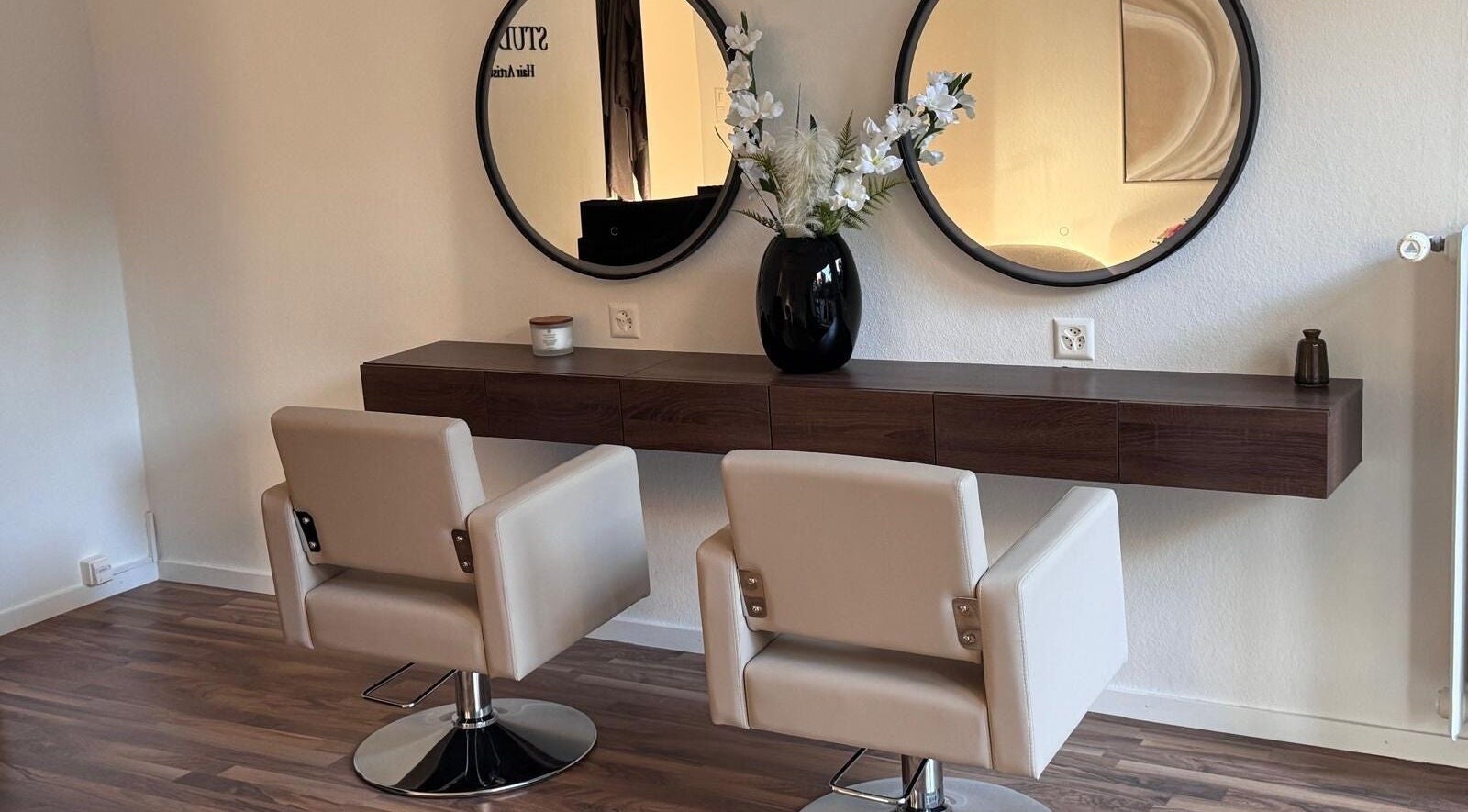 Espace coiffeur moderne chez MC Studio Hair Artist à Lausanne, Vaud, CH avec miroirs et fauteuils beiges.
