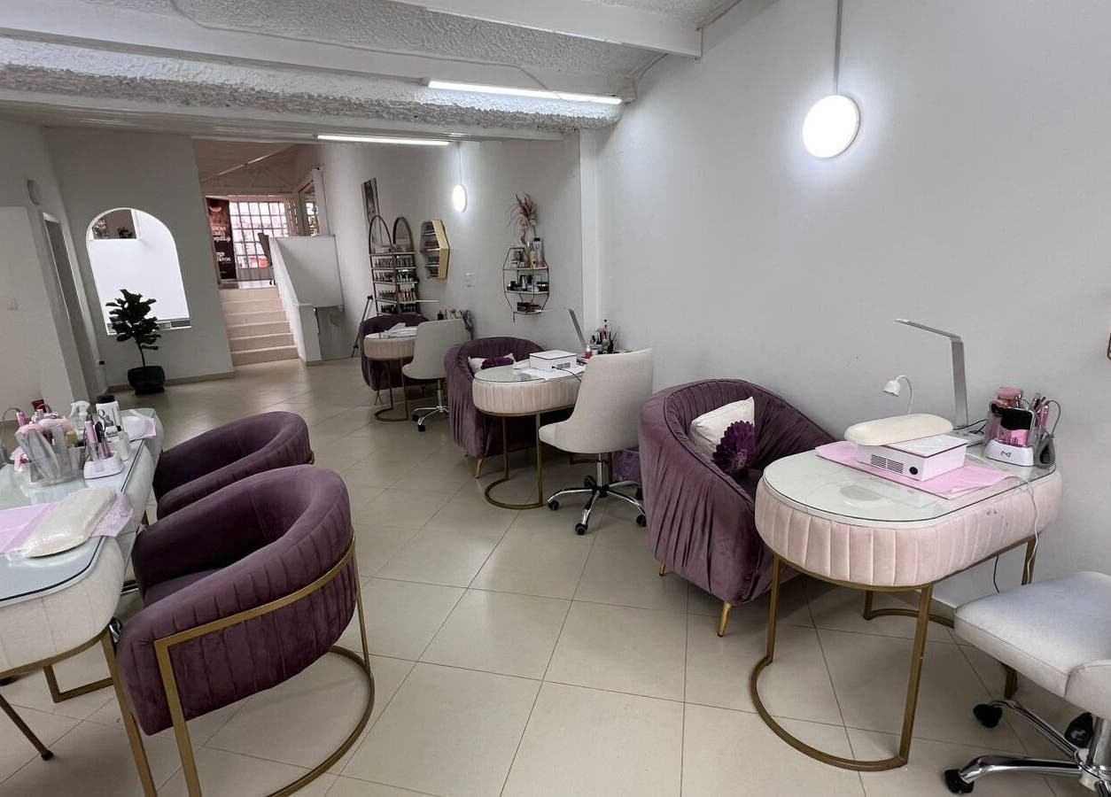Interior de ROSIE BEAUTY STUDIO en Bogotá, D.c., con elegantes sillas púrpuras y estaciones de belleza modernas.