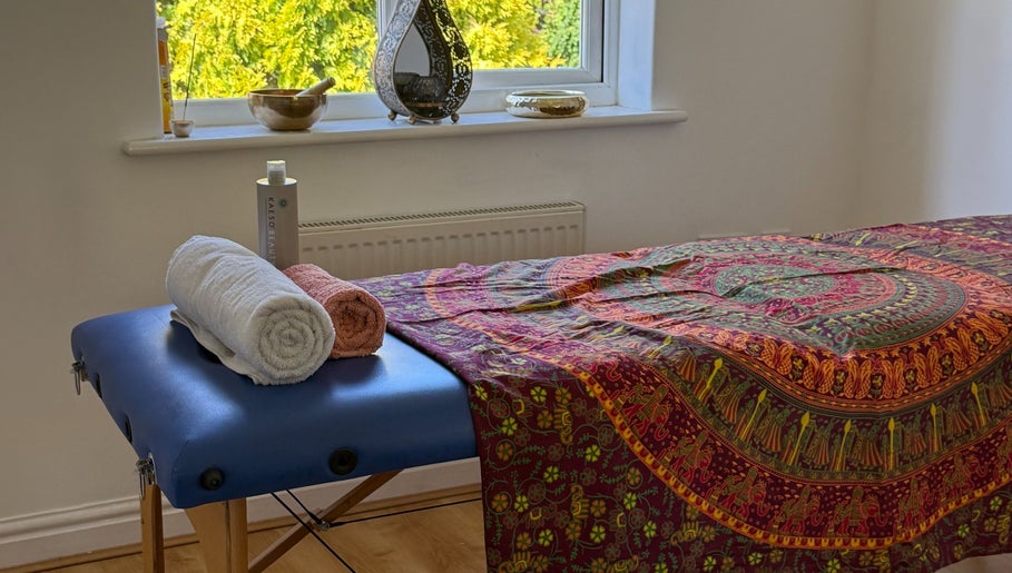 Massage table at Healing Hands, Spalding, England, GB adorned with colorful linen and neatly folded towels.