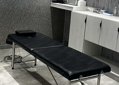 غرفة تدليك في Al-Nahat، عمان، عمان ووجود سرير تدليك أسود وديكور هادئ.