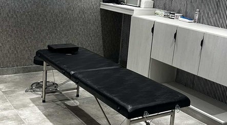 غرفة تدليك في Al-Nahat، عمان، عمان ووجود سرير تدليك أسود وديكور هادئ.