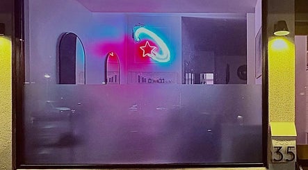 Vibrant neon star at Danielle Frances Hair in Toronto, Ontario, CA, seen through the salon's modern window.