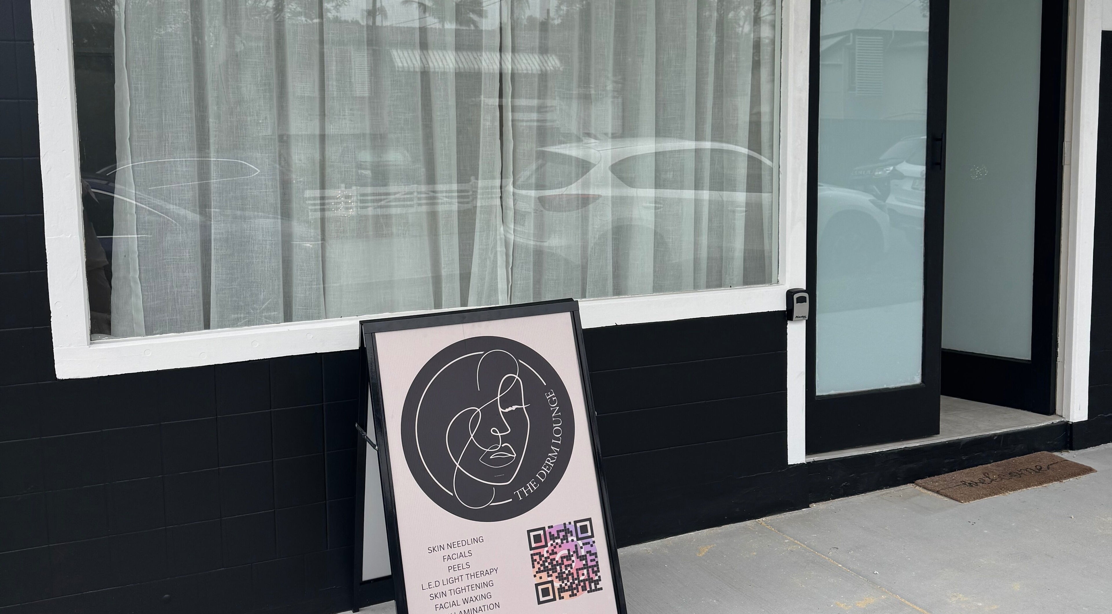 Entrance of The Derm Lounge at Woody Point, Queensland, AU with a services sign.