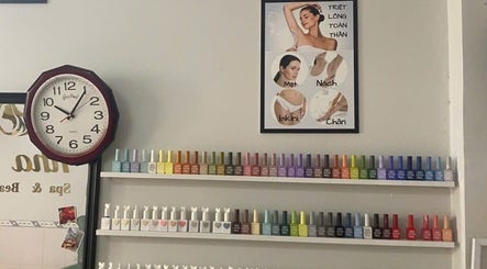 Colorful nail polish display at Oi Nha Trang Spa, Nha Trang, Khánh Hòa, VN, under a clock and beauty poster.