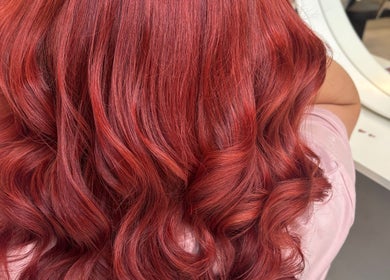 Vivid red curly hairstyle at Levre Beauty, London, England, GB, showcasing brilliant hair color transformation.