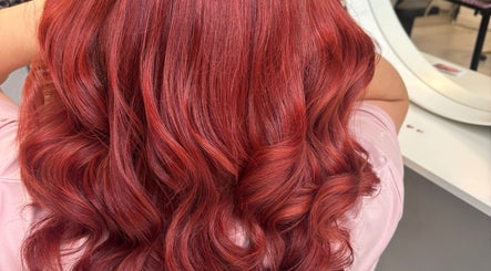 Vivid red curly hairstyle at Levre Beauty, London, England, GB, showcasing brilliant hair color transformation.
