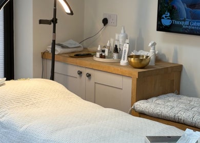 Calming treatment room at Glow by Mykala, Carlton, England, GB with cozy bed and luxury skincare products.