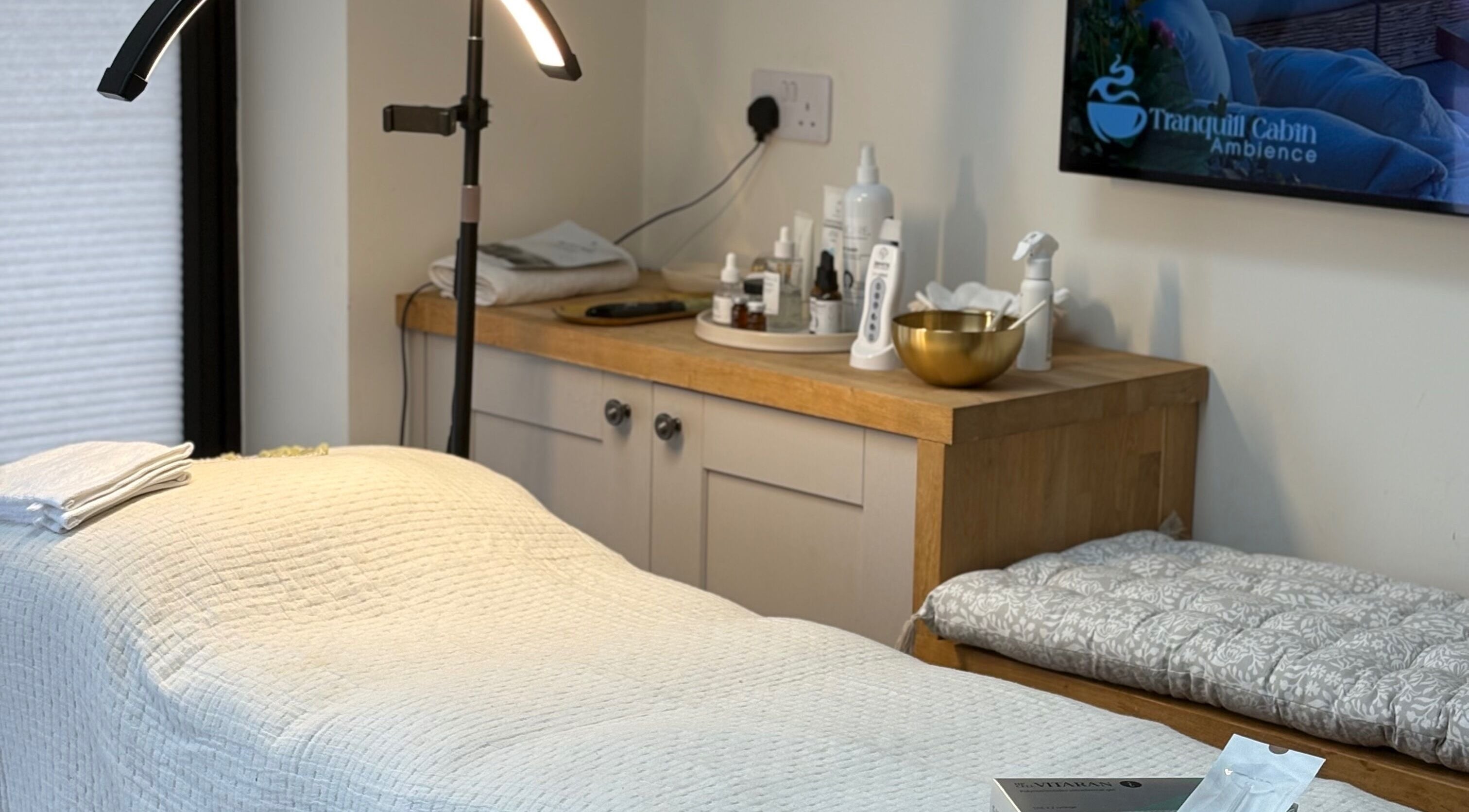 Calming treatment room at Glow by Mykala, Carlton, England, GB with cozy bed and luxury skincare products.