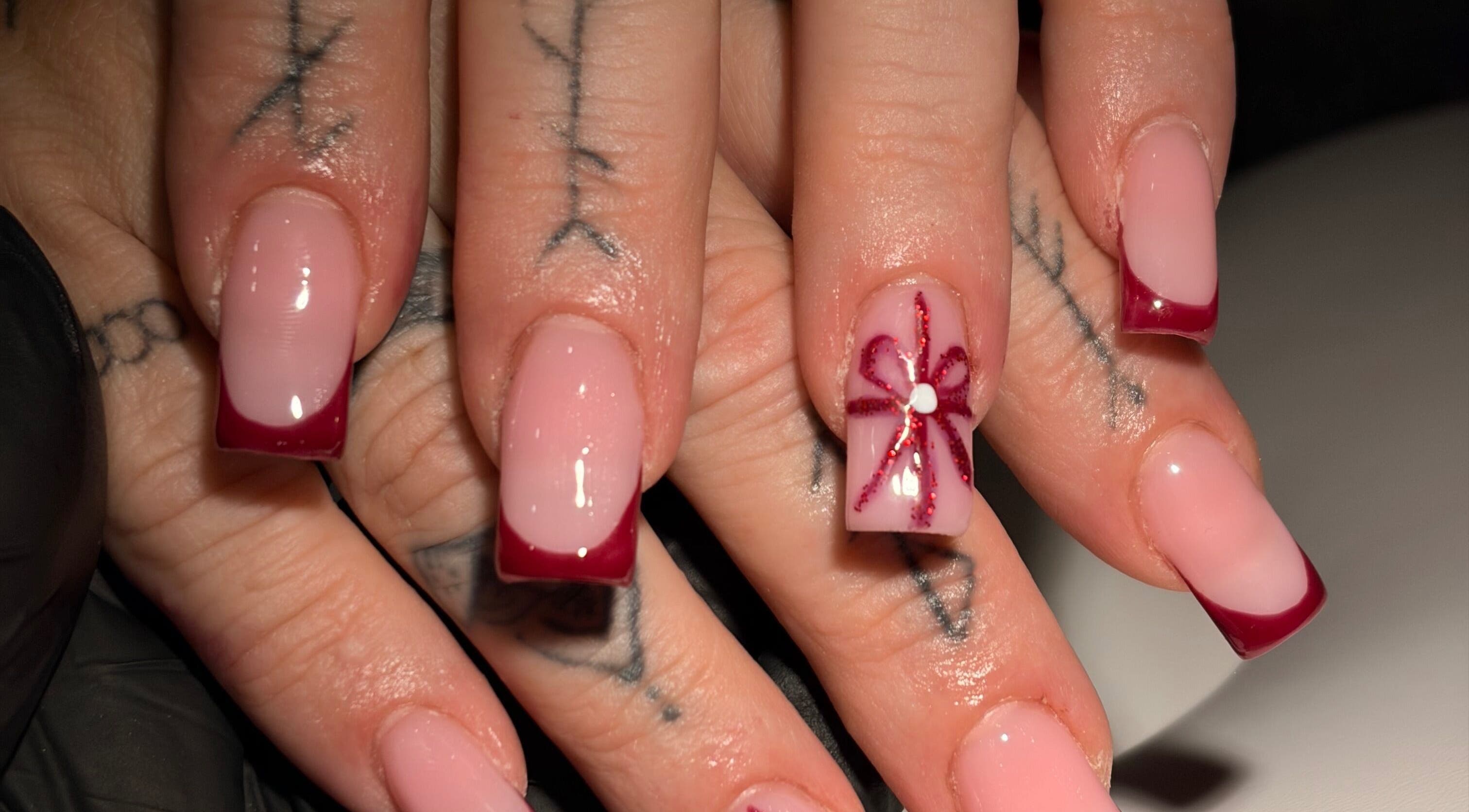 Elegant nail art with red tips and flower design at Niamh&Co, Stanford-le-hope, England, GB.