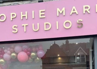 Hindle Luxx Aesthetics storefront in Manchester, England, with pink and gold balloon decor.