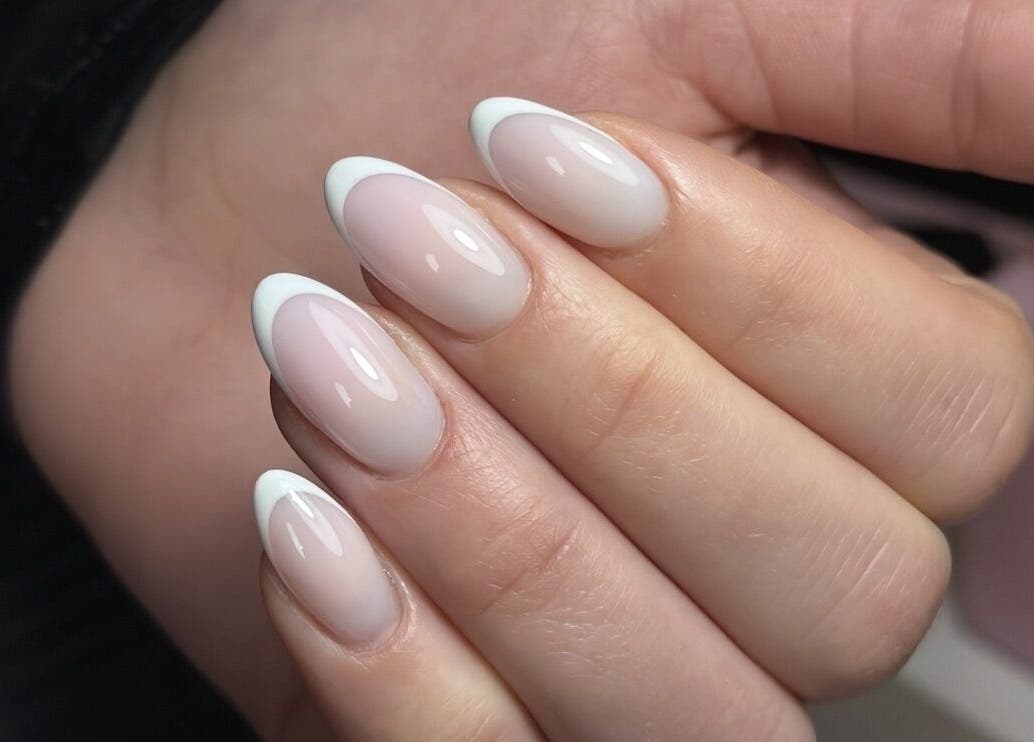 Chic French manicure at Lustrée Nails, Northampton, England, GB. Glossy nude nails with white tips.