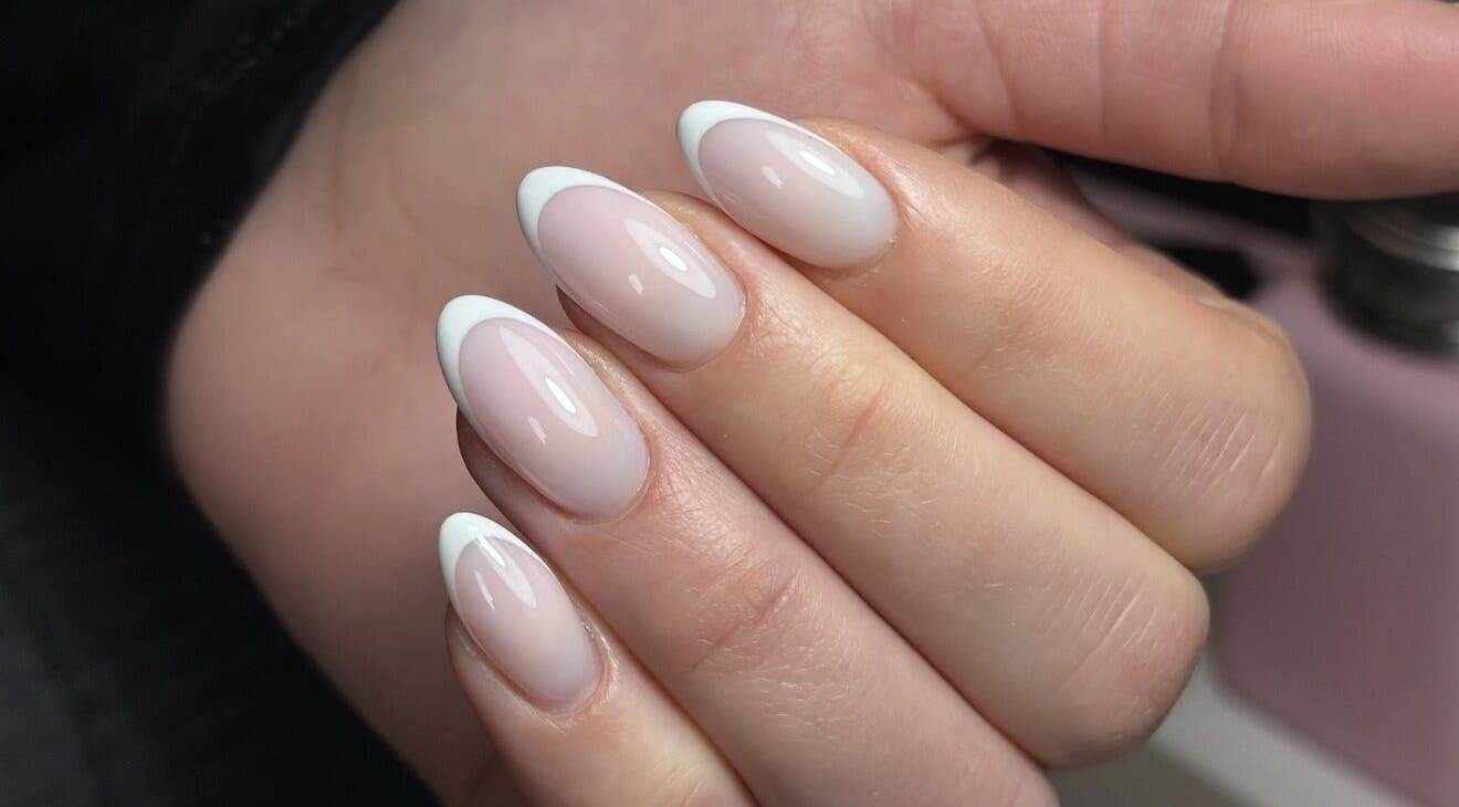 Chic French manicure at Lustrée Nails, Northampton, England, GB. Glossy nude nails with white tips.