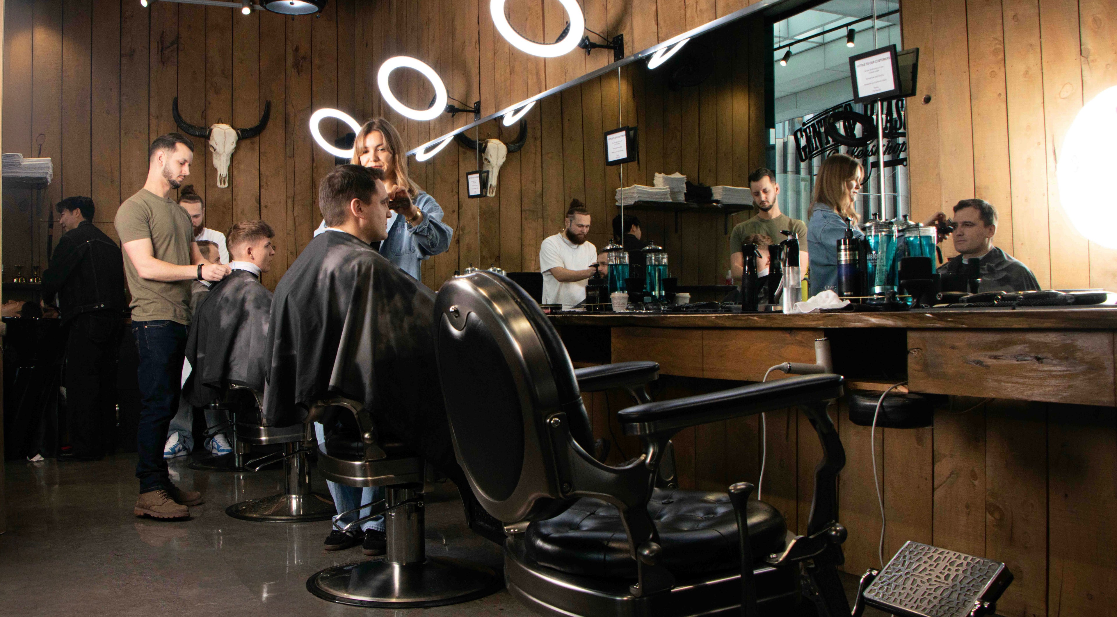 Modern barbershop interior at Gents & Rascals, HSBC tower, Auckland, NZ with customers receiving haircuts.