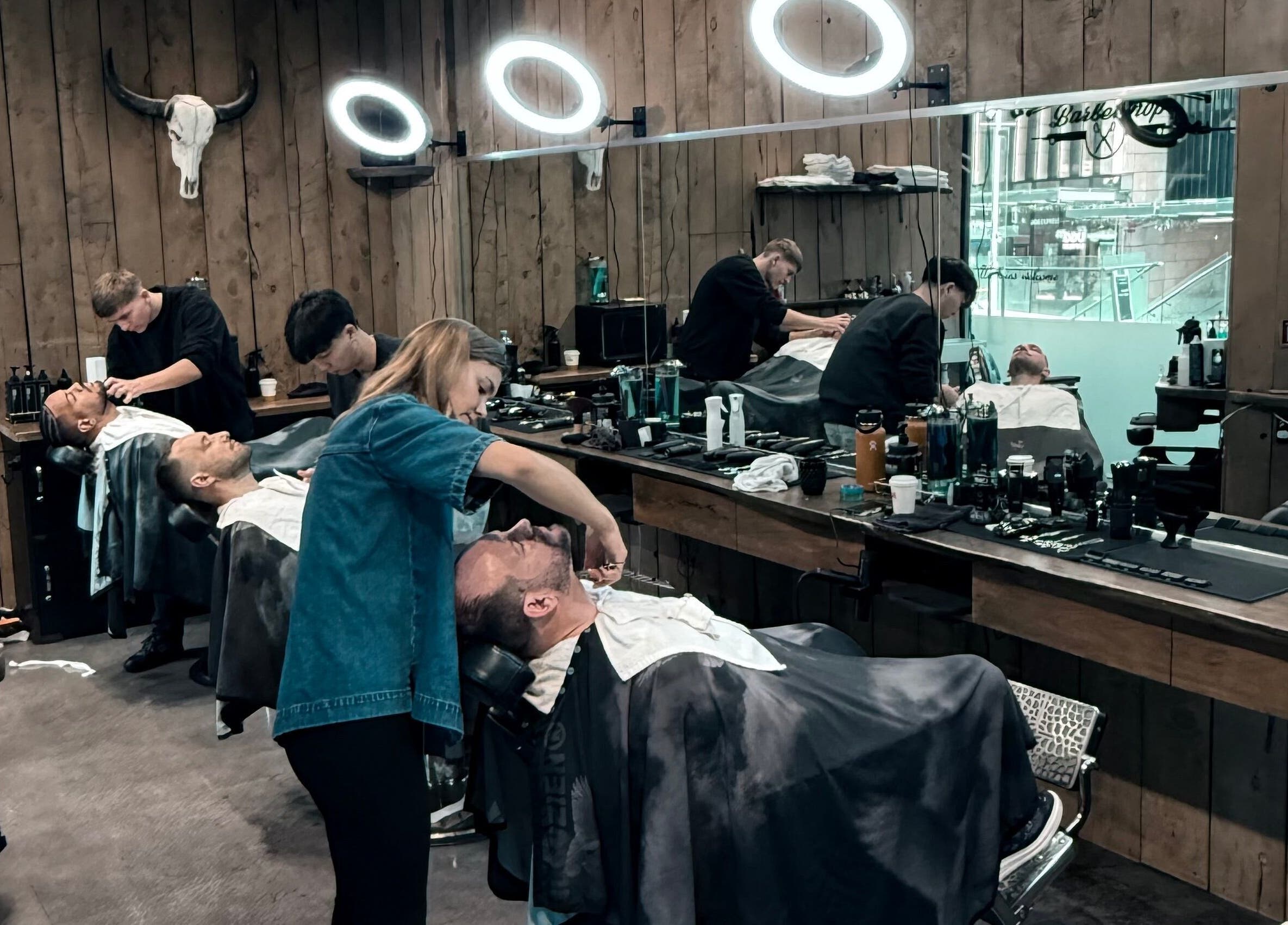 Stylish interior of Gents & Rascals barbershop, HSBC tower, Auckland, NZ, with customers receiving haircuts.