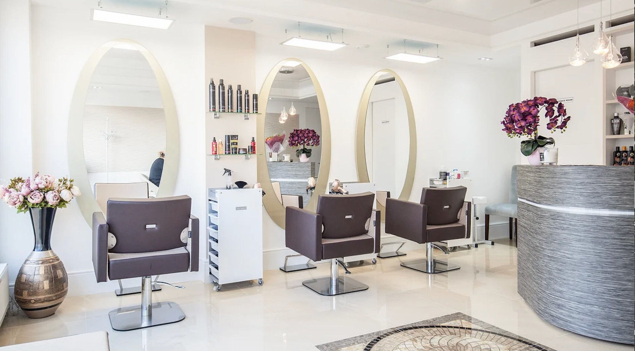 Chic interior of AASTHA hair and beauty, London, England, GB with elegant styling chairs and large mirrors.