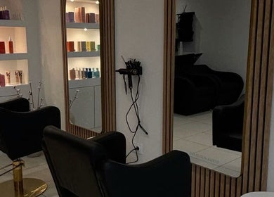 Intérieur élégant de Maison Afro à Toulouse, Occitanie, FR avec fauteuils noirs et étagères de produits.