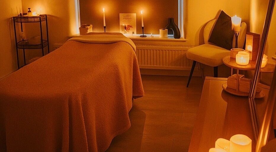 Cozy treatment room at Therapeutic Beauty in Toddington, England, GB lit by warm candlelight.