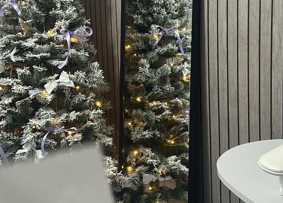 Beauty By Yas in Attleborough, England, GB, features a brightly lit, snowy Christmas tree with purple ribbons.