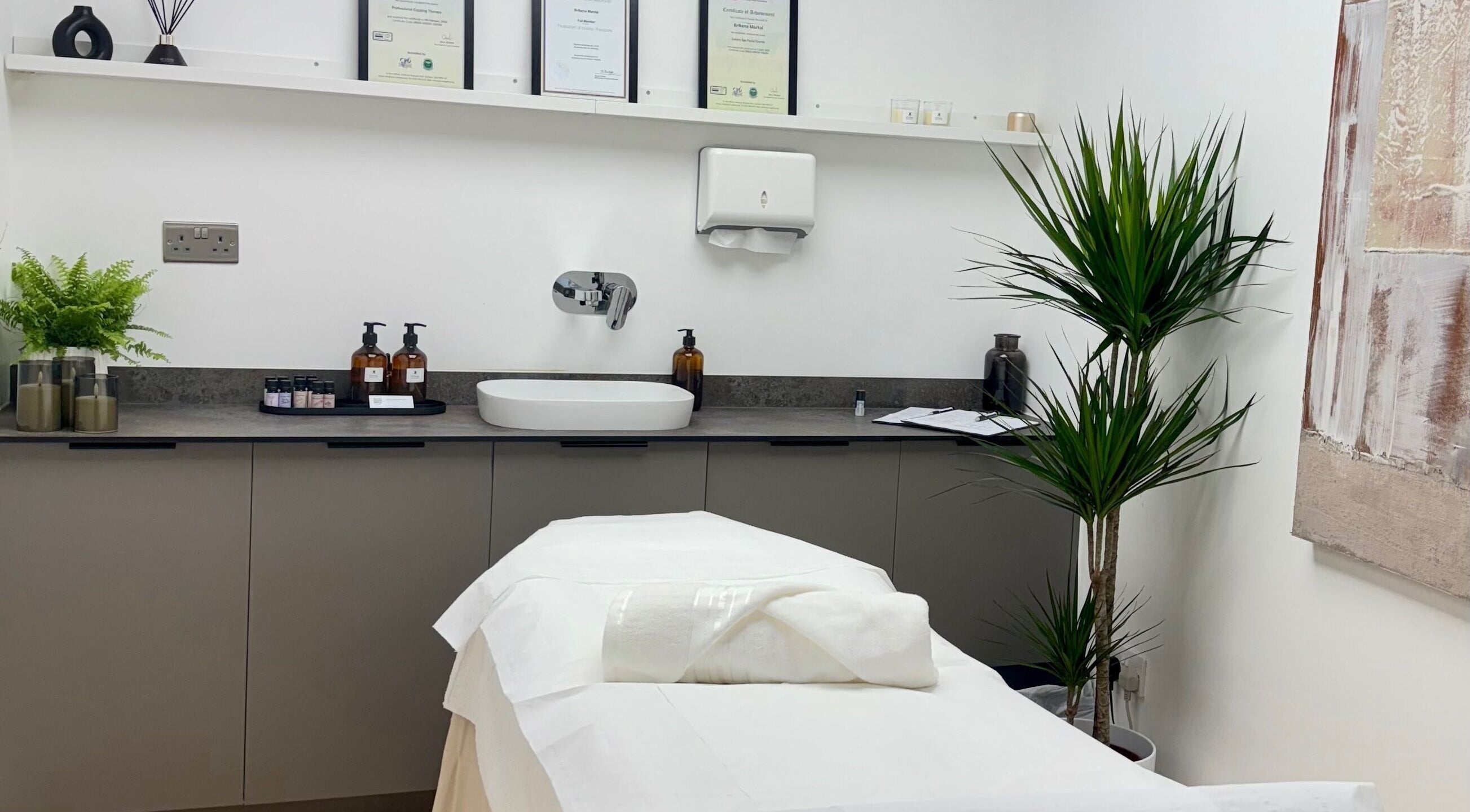 Serene treatment room at Kenna Wellness & Spa, London, England, GB featuring a cozy massage bed and soothing plants.