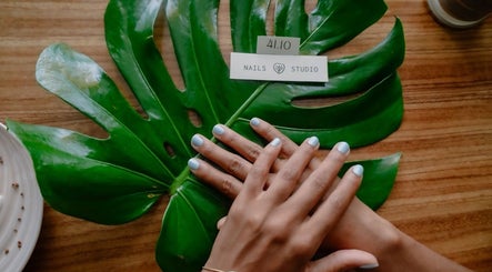 Manos con manicura azul claro en 41.10 Nails Studio, Tulum, Quintana Roo, MX, sobre hoja verde.
