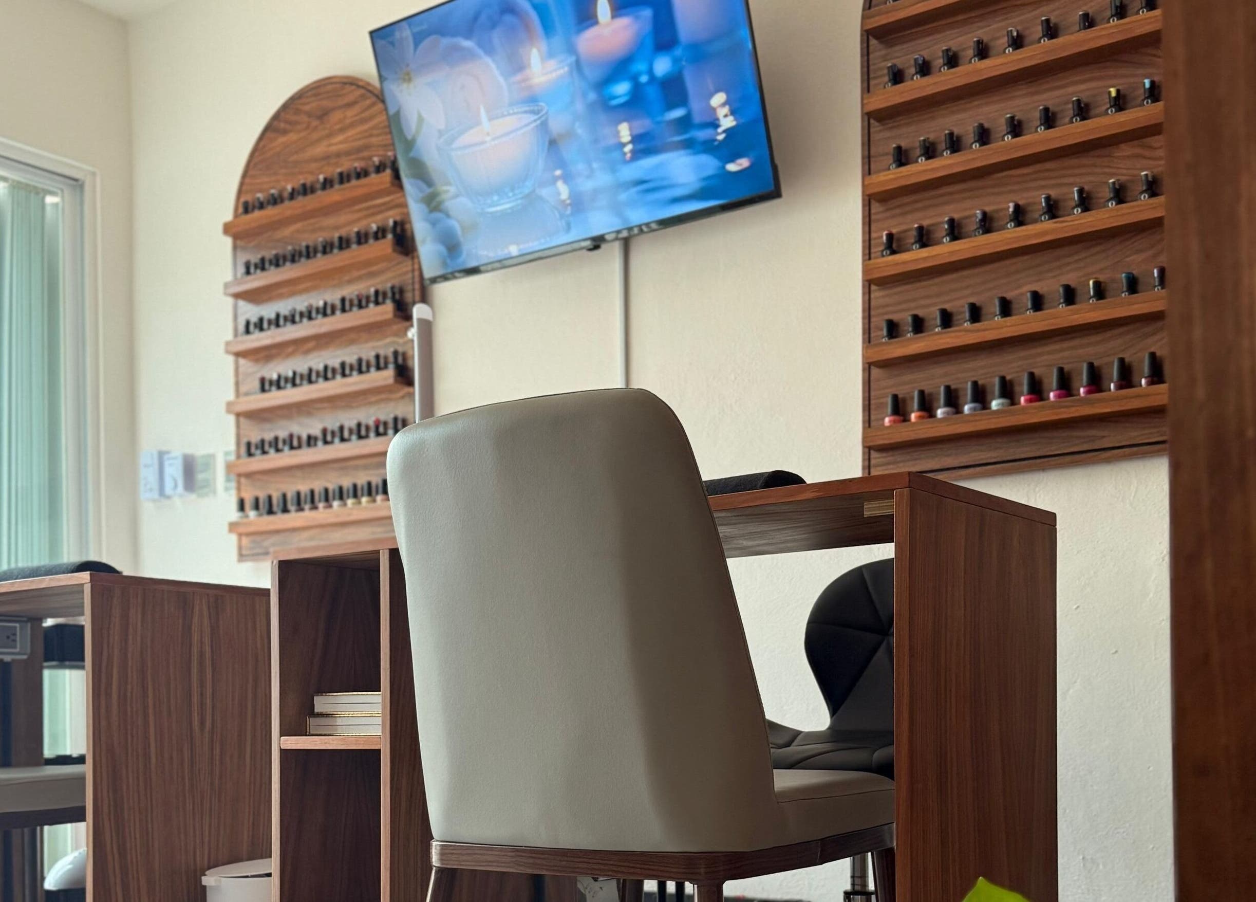 Interior de 41.10 Nails Studio en Tulum, Quintana Roo, MX con elegantes mesas y sillas frente a un televisor.