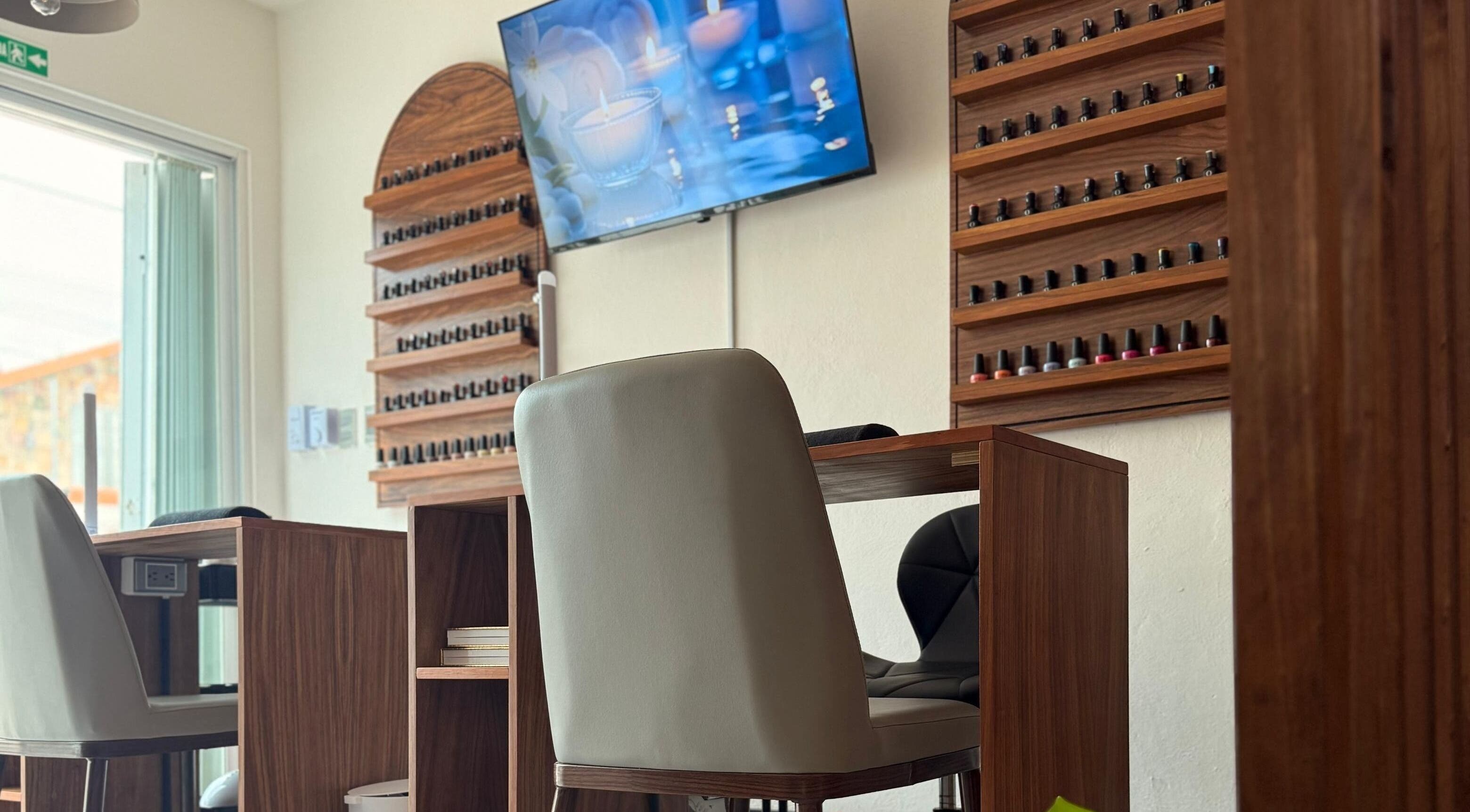 Interior de 41.10 Nails Studio en Tulum, Quintana Roo, MX con elegantes mesas y sillas frente a un televisor.