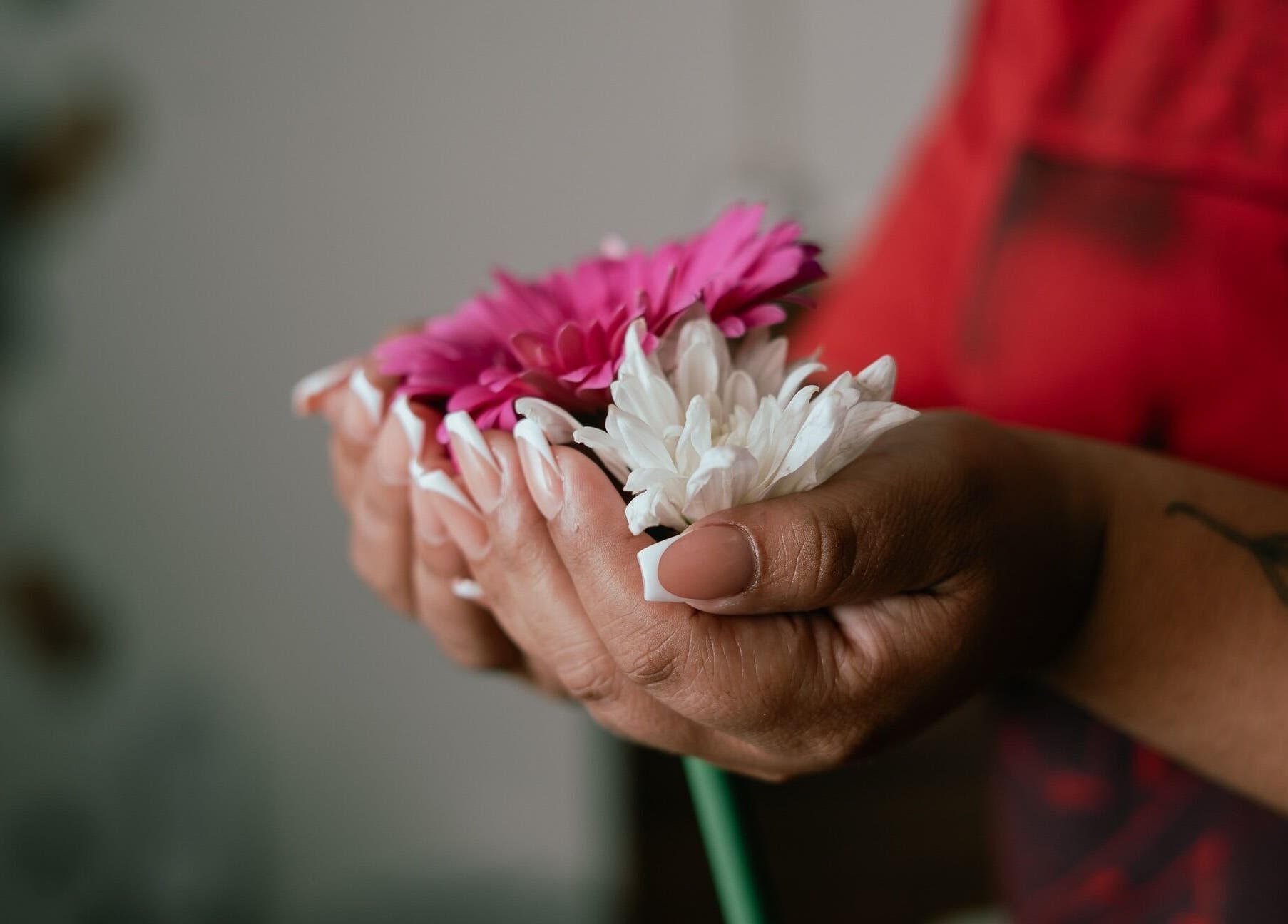 Manos con manicura francesa sosteniendo flores en 41.10 Nails Studio, Tulum, Quintana Roo, MX.