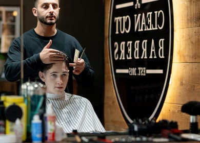 Barber at Clean Cut Barbers in Caringbah South, NSW, AU styling a client's hair with focused attention.