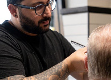 Stylist at Clean Cut Barbers, Caringbah South, NSW, AU, expertly trimming a client's hair.