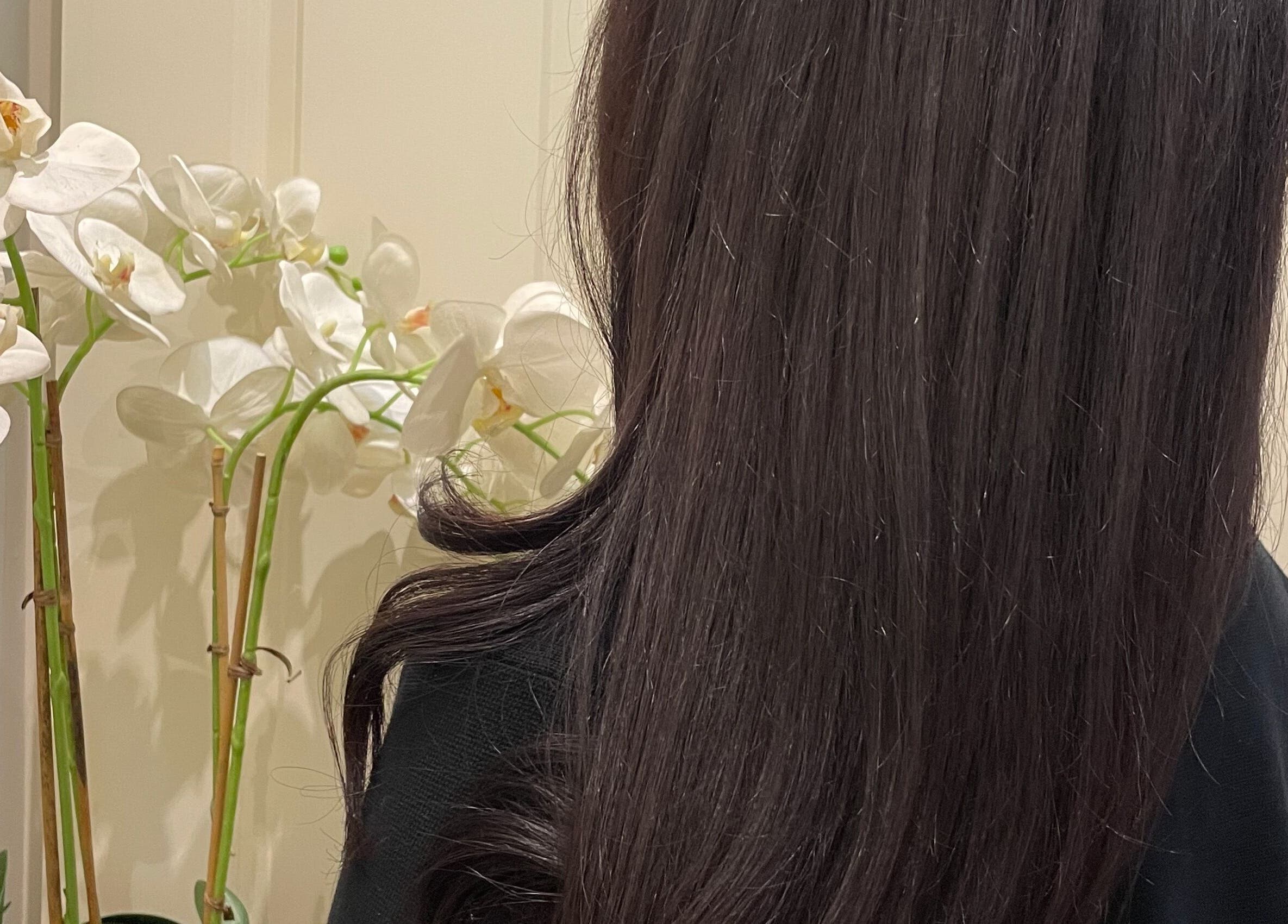 Lustrous hair beside orchids at Sophie Michelle Hair, London, England, GB. Beauty and wellness ambiance.