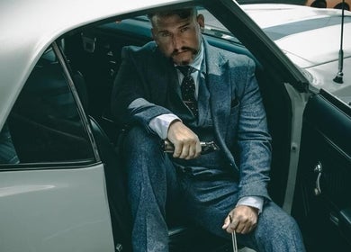 Man in a suit sitting in a car outside Webster & Carr, Newcastle upon Tyne, England, GB.