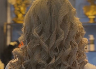 Blonde curly hairstyle at Vogue & Volume, Il-ħamrun, MT with stylish decor in background.
