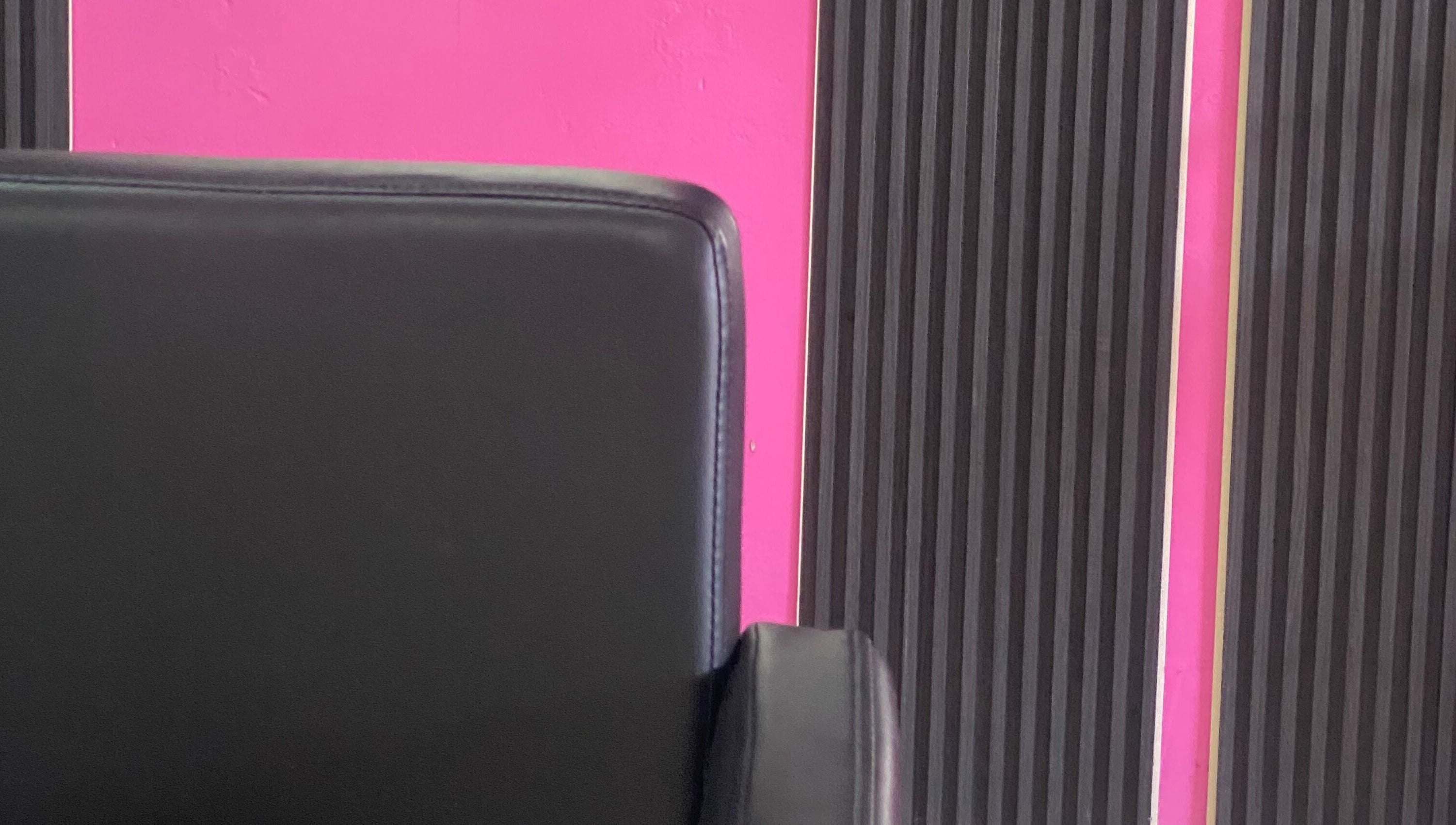 Modern black salon chair against pink and black wall at DopexBraids, Bridgetown, Saint Michael, BB.
