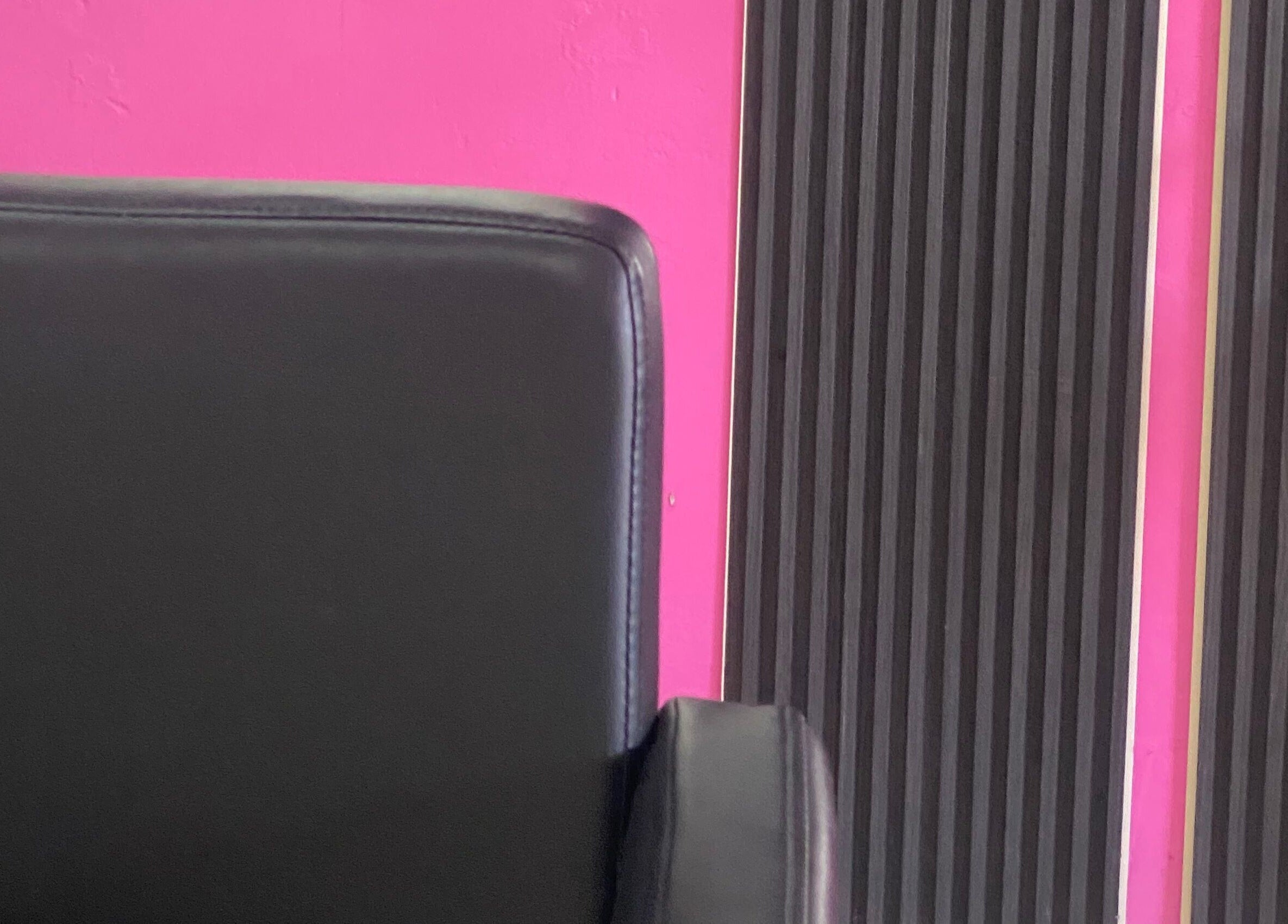 Modern black salon chair against pink and black wall at DopexBraids, Bridgetown, Saint Michael, BB.