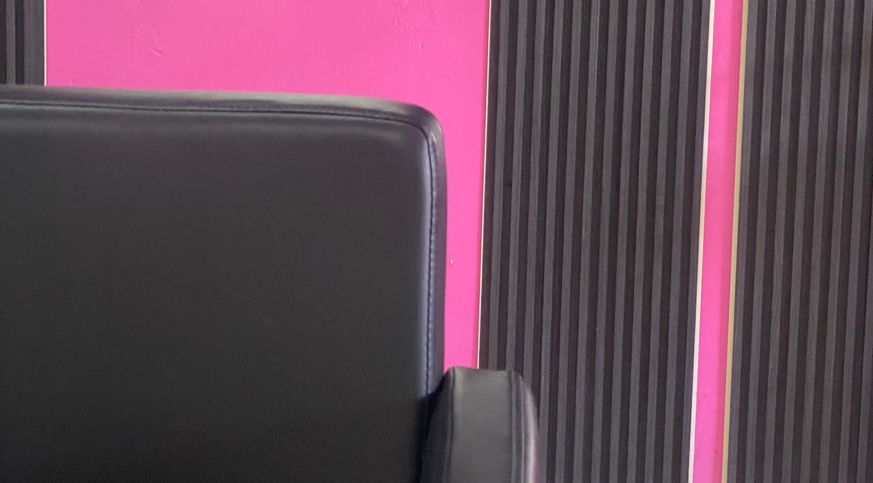 Modern black salon chair against pink and black wall at DopexBraids, Bridgetown, Saint Michael, BB.